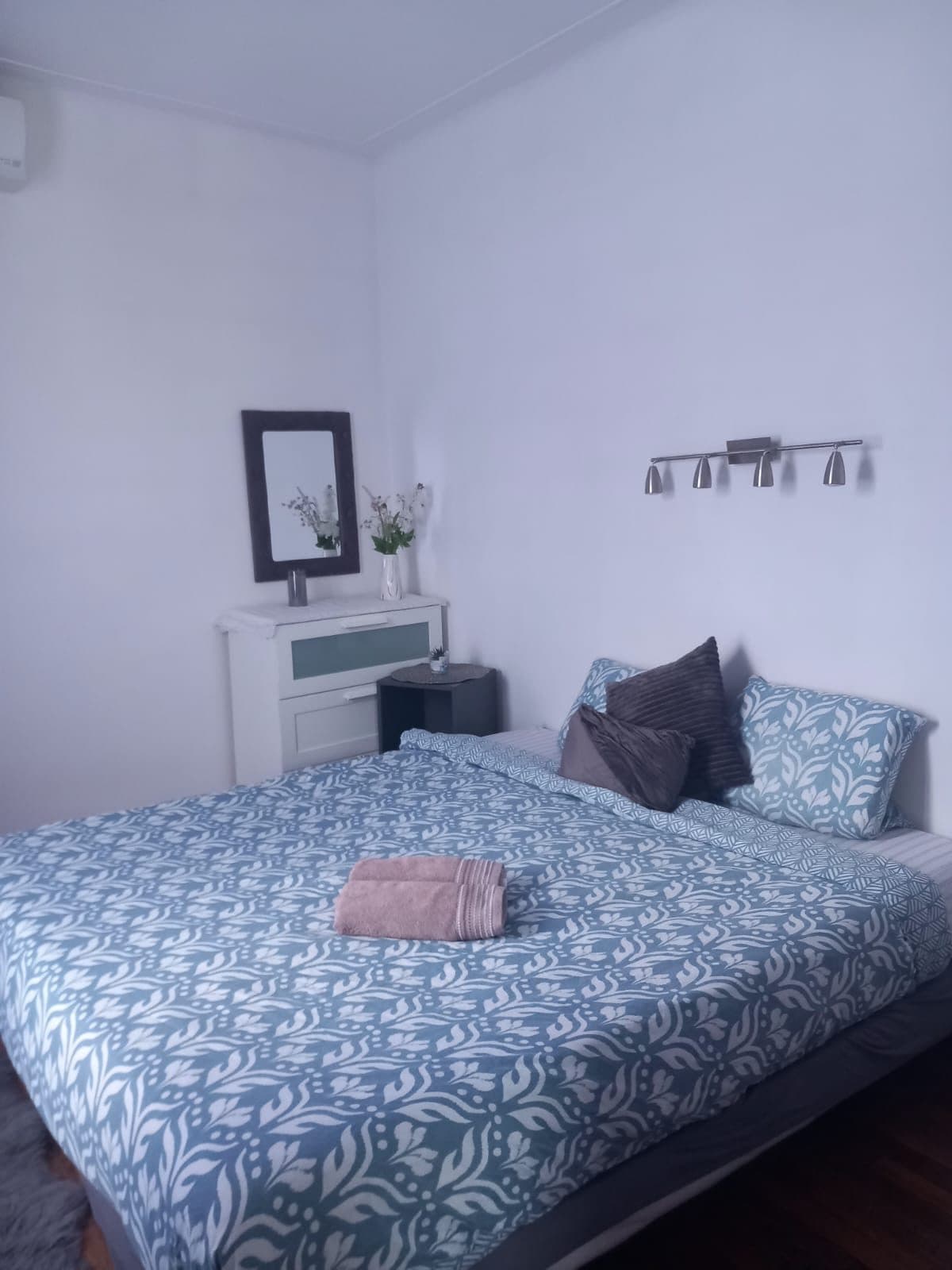 Chambre rangée avec lit fait et linge de lit bleu à motifs