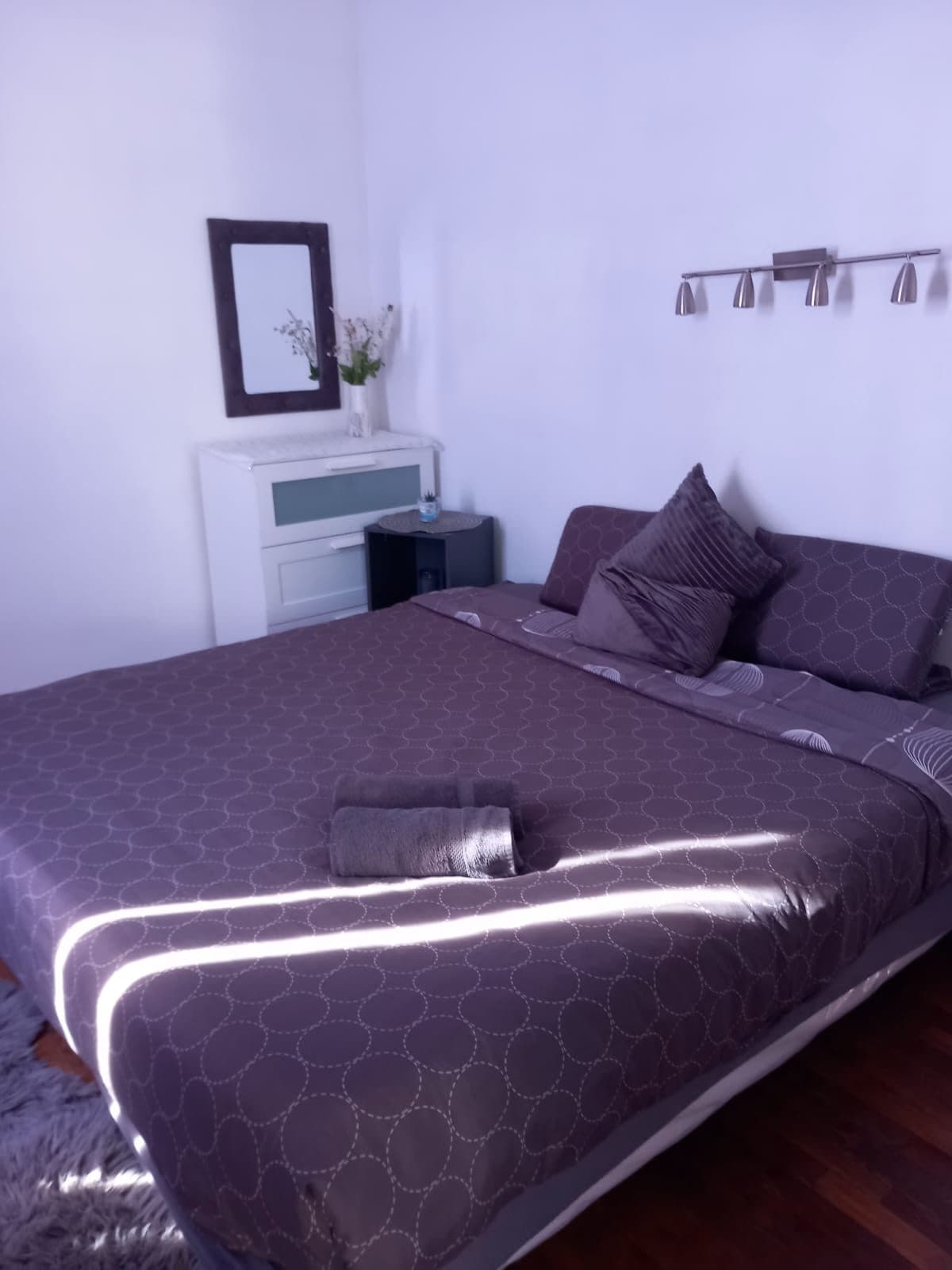 Chambre lumineuse avec couvre-lit prune et commode blanche
