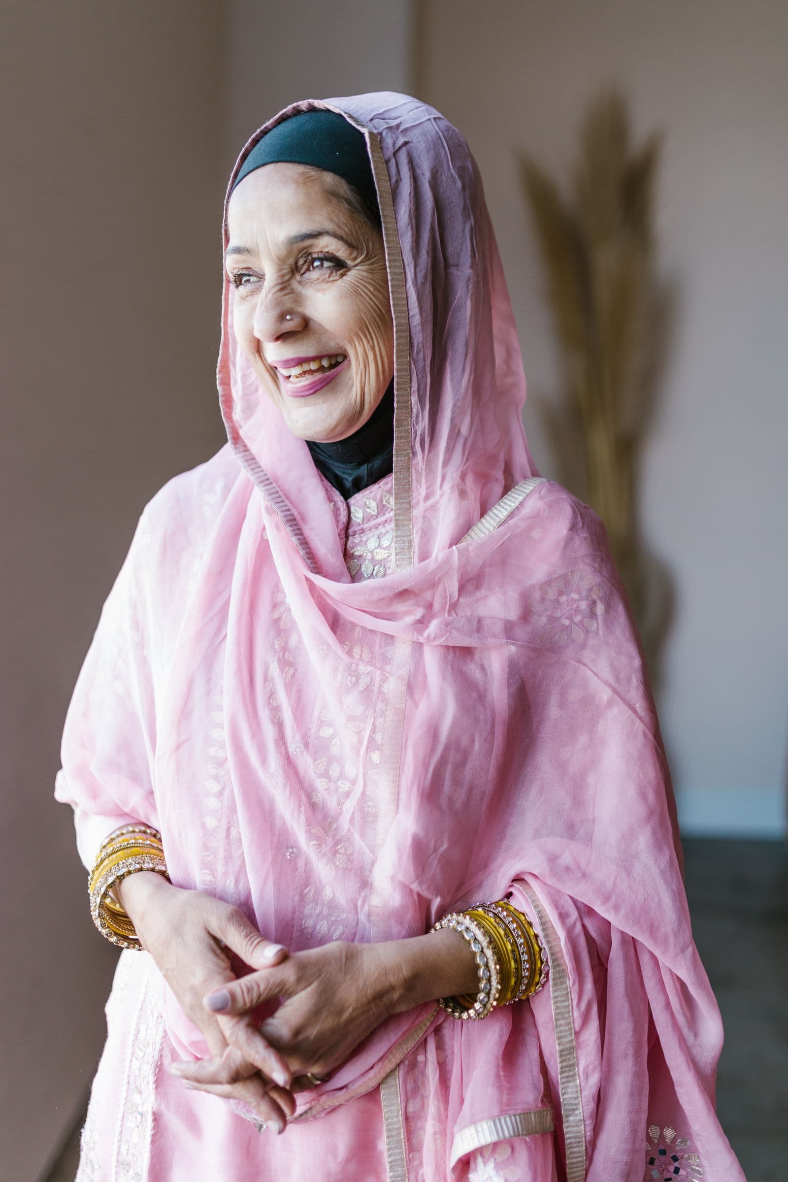 Aînée souriante en voile rose pâle, sereine dans son salon