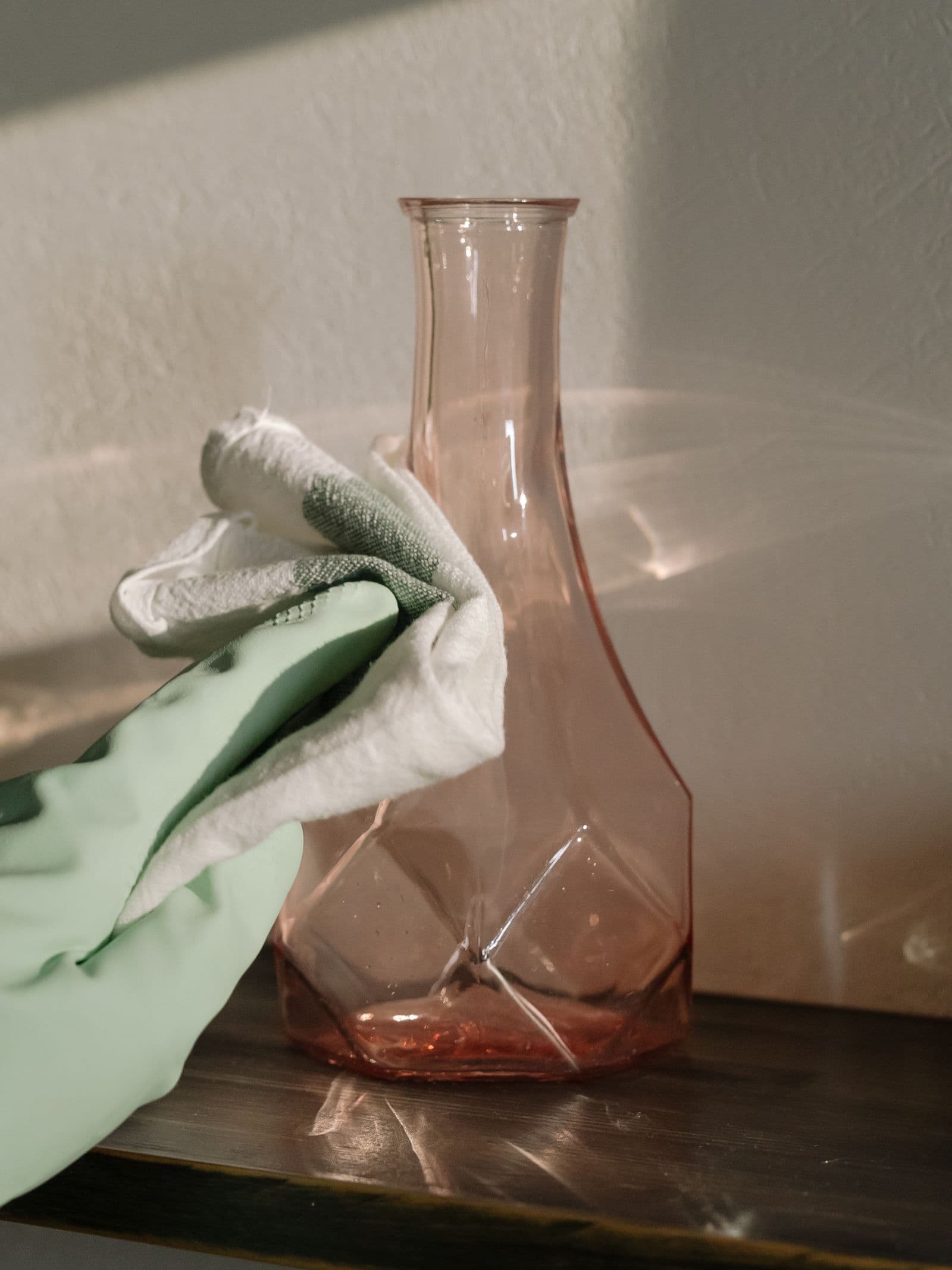 Dépoussiérage délicat d'un vase en verre rose avec un chiffon doux