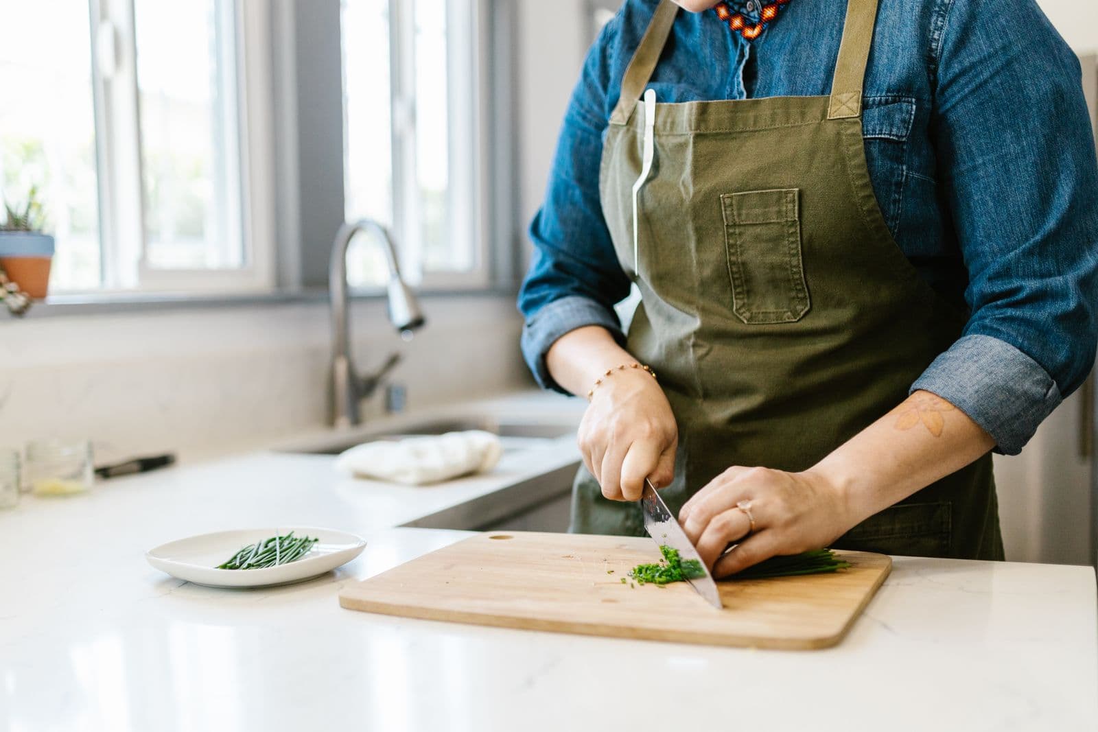 Ciboulette ciselée sur une planche dans une cuisine baignée de lumière